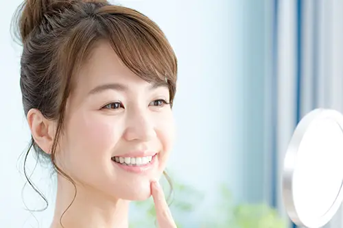 鏡で歯を見る女性