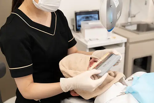 歯にシェードガイドをあてる歯科衛生士